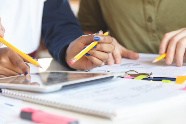 Cropped shot of dark and white skinned hands of office workers or financial analytics holding yellow