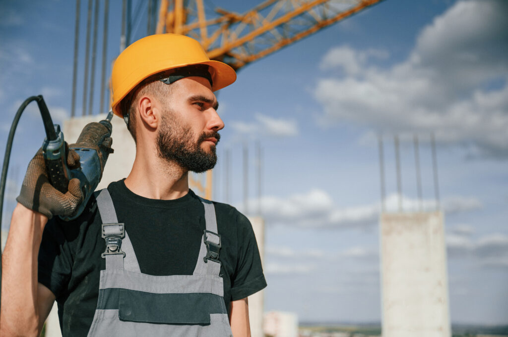 Portrait of man that is in uniform with the drill on the construction site