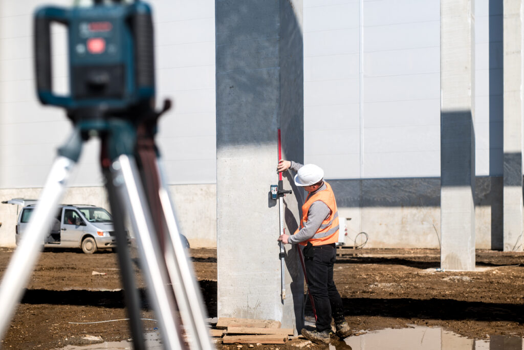 Industrial surveyor on construction site, working with thodolite, gps system and level machine