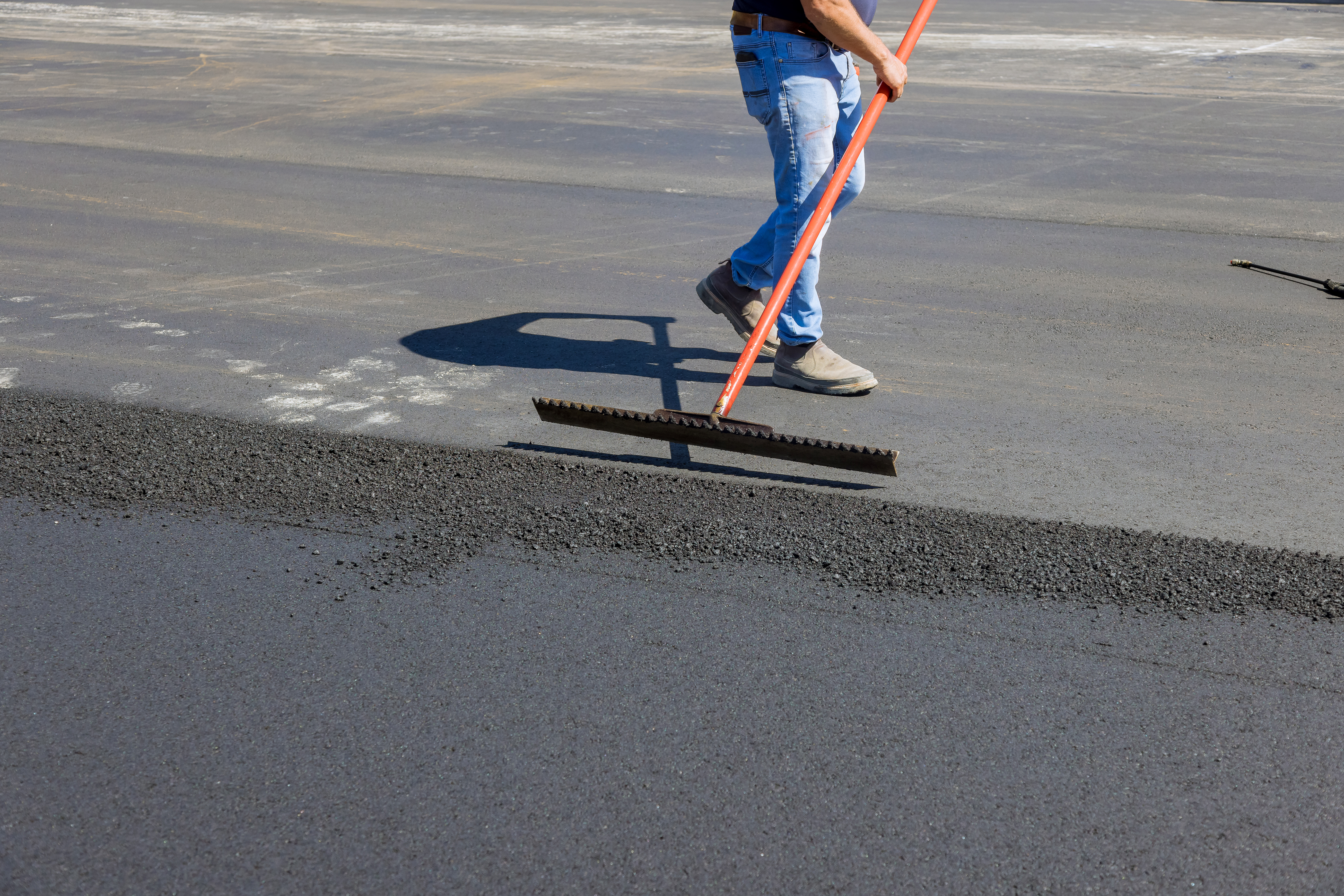 Laying asphalt with working men shoveling black gravel for on the road